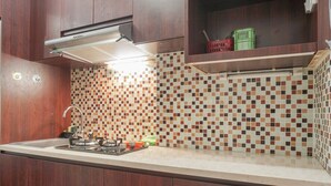 Una cocina con armarios de madera, salpicadero de azulejos y encimera con estufa a gas y lavabo.