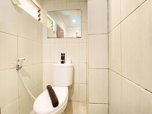 A small, clean bathroom with white tiles, a toilet, a towel, and a mirror. - Modern And Cozy Stay 2Br Apartment At Gateway Ahmad Yani Cicadas (Bandung)