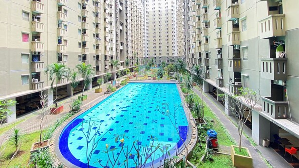 A residential building with a swimming pool surrounded by greenery and balconies. - Modern And Cozy Stay 2Br Apartment At Gateway Ahmad Yani Cicadas (Bandung)