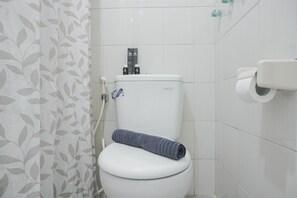 Inodoro con dispensador de papel higiénico y una toalla sobre el asiento.