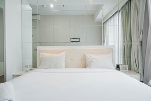 A modern hotel room with a large bed, a bedside table, and a mirror.