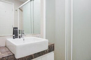 A bathroom with a white sink, a marble countertop, and a large mirror. - Stunning And Strategic 2Br Apartment At Casa Grande Residence (Jakarta)