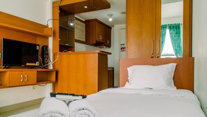 A hotel room with a bed, a TV, wooden cabinets, and a mirror.