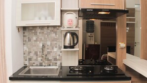 Une cuisine compacte équipée d’une cuisinière à gaz, d’une bouilloire et d’une machine à café, le tout posé sur un plan de travail.