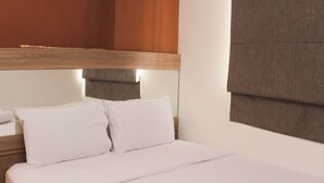 Un lit bien fait, avec du linge de lit blanc et une tête de lit en bois.