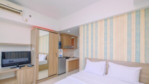 A hotel room with a bed, a TV, a mini-fridge, a microwave, and a small kitchen area. - Comfort Stay Studio Room At Margonda Residence 3 Apartment (Depok)