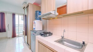 A kitchen with a sink, a water dispenser, a refrigerator, and a stove. - Comfort Stay Studio Room At Margonda Residence 3 Apartment (Depok)
