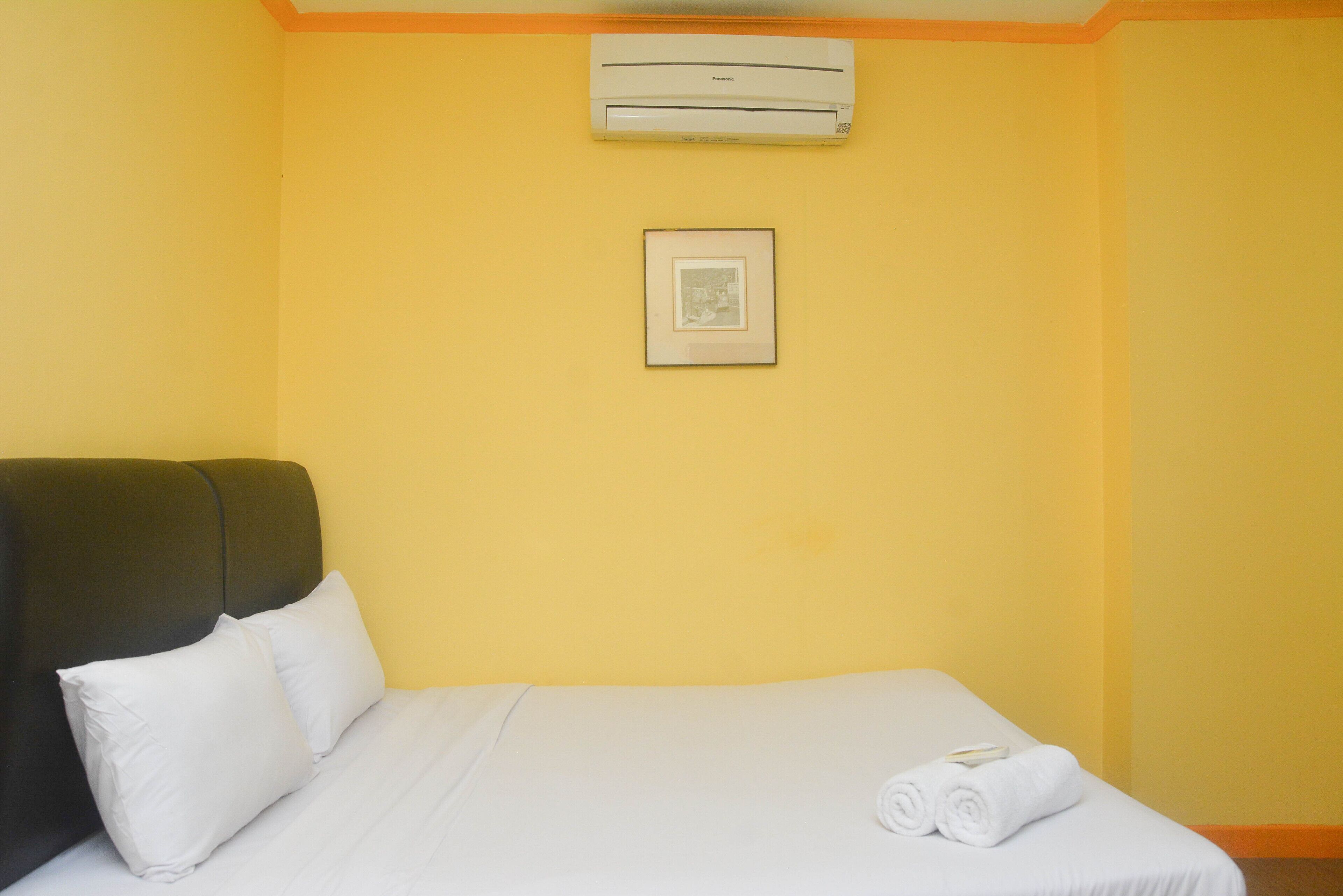 Ein Hotelzimmer mit Bett, Kissen, einem gerahmten Bild und einer Klimaanlage.
