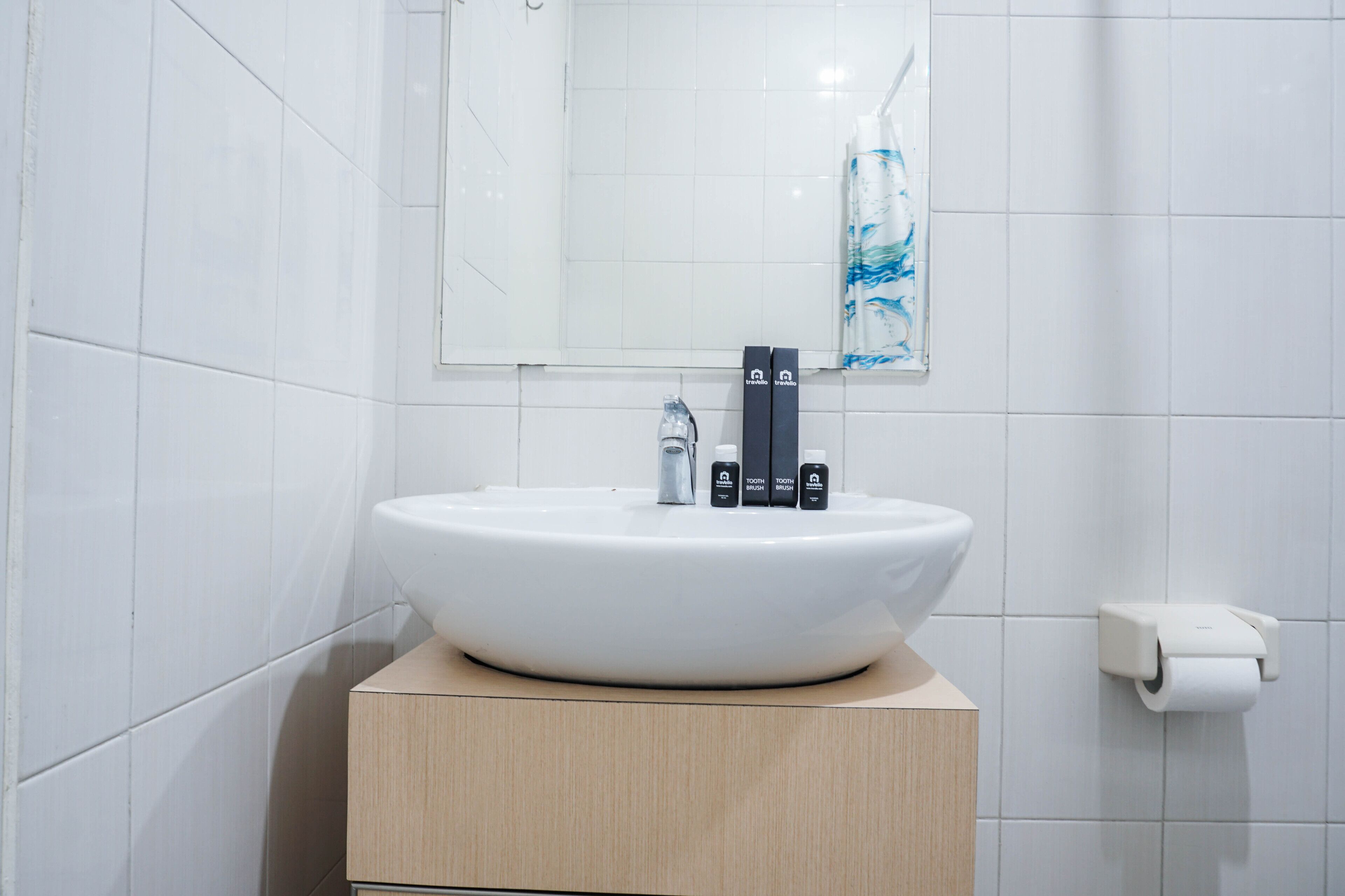 Ein Badezimmer mit einem weißen Waschbecken, einem Spiegel und einem Toilettenpapierhalter.
