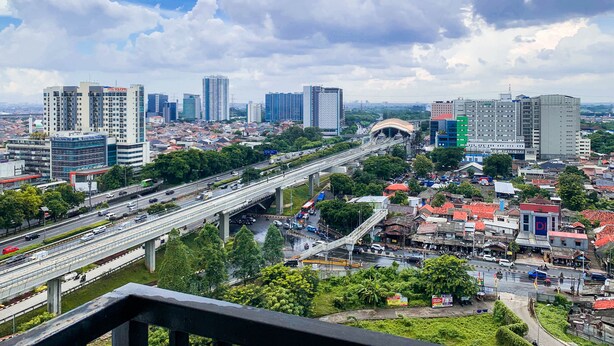 A cityscape with high-rise buildings, a highway, and a pedestrian bridge. - Graceful And Cozy 2Br At Signature Park Grande Apartment (Jakarta)
