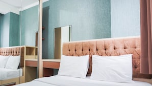A hotel room with a large bed, a wooden nightstand, a mirror, and a view of the city. - Graceful And Cozy 2Br At Signature Park Grande Apartment (Jakarta)