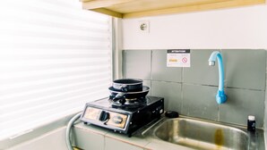 Una cocina compacta con estufa a gas, un lavamanos y armarios de madera.
