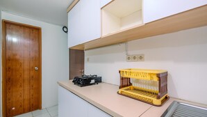 Una cocina con una puerta de madera, una encimera, una cesta amarilla y un electrodoméstico negro.