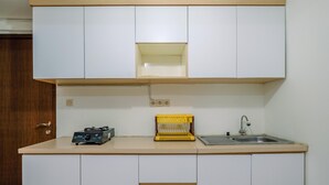 Una pequeña cocina con armarios blancos, una cesta amarilla y un lavamanos.
