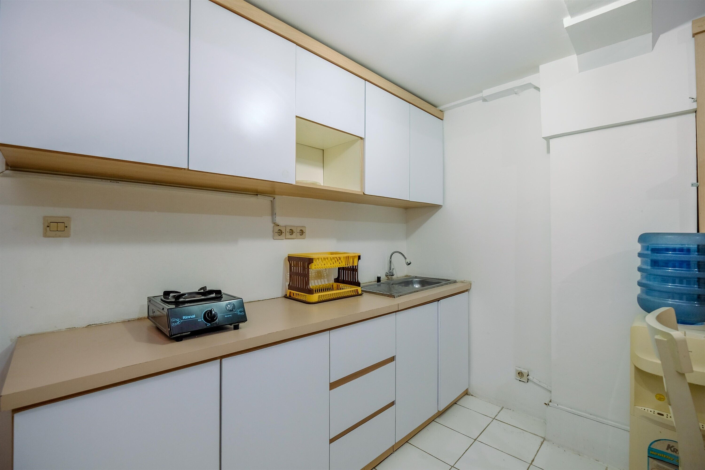 A small kitchen with white cabinets, a wooden countertop, a gas stove, a sink, and a water dispenser.