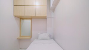 Una habitación pequeña con cama individual, un armario de madera sobre la cama y una ventana en la pared izquierda.