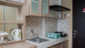 A compact kitchen with a sink, a kettle, a toaster, and a small countertop. - Modern And Relax Studio Room At Serpong Greenview Apartment (South Tangerang)