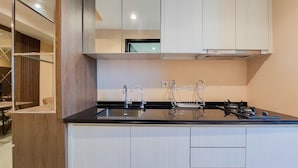A modern kitchen with a black countertop, stainless steel sink, and white cabinetry. - Nice And Comfort 1Br At Branz Bsd City Apartment (Pagedangan)