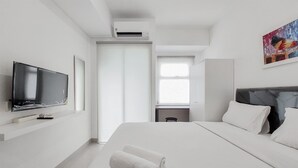 Moderni hotellihuone, jossa on taulutelevisio, siististi pedattu sänky ja taulu seinällä.