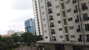 A multi-story residential building with balconies, a parking area, and a pedestrian walkway. - Cozy And Tidy 2Br At Signature Park Grande Apartment (Jakarta)