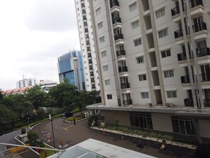 A multi-story residential building with balconies, a parking area, and a pedestrian walkway.