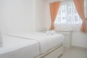 A bedroom with a bed, a nightstand, and a window with curtains.