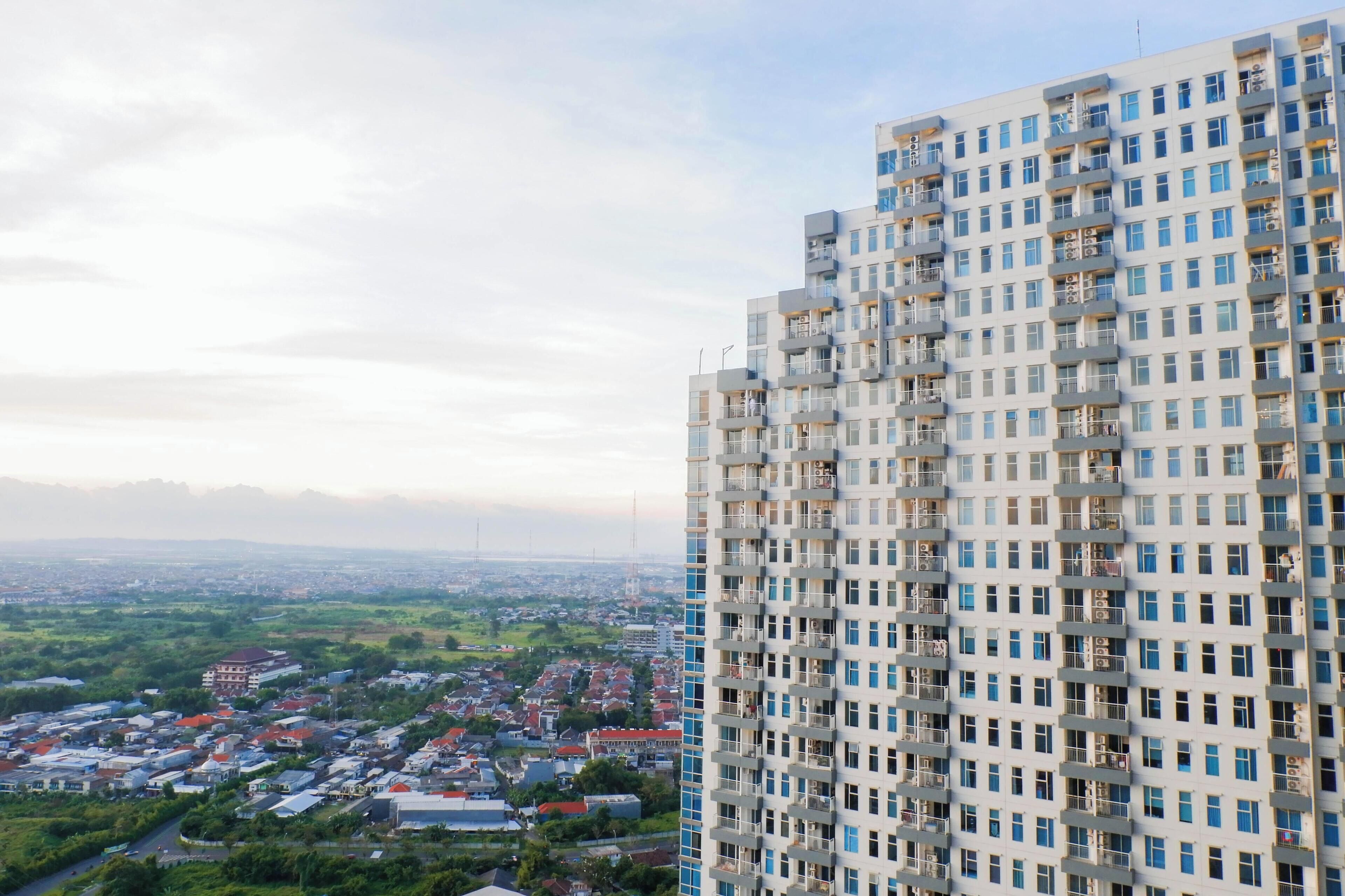 A high-rise building with multiple balconies and a view of a cityscape in the background.