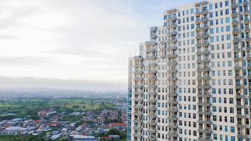 A high-rise building with multiple balconies and a view of a cityscape in the background.