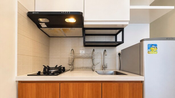 A kitchen with a gas stove, a double sink, and a refrigerator.