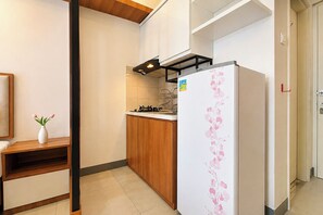 A compact kitchen with a refrigerator, wooden cabinets, and a small countertop.
