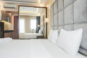 A hotel room with a large bed, a mirror, and a view of the bathroom. - Warm & Cozy Studio At Signature Park Grande Apartment (Jakarta)