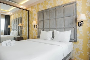 A hotel room with a large bed, a headboard, two wall-mounted lamps, and a mirror. - Warm & Cozy Studio At Signature Park Grande Apartment (Jakarta)