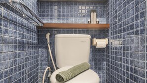 Un bagno con il water, un asciugamano e uno scaffale con articoli da toilette.