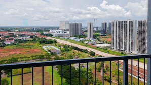 A high-rise building with multiple floors, a large parking area, and a view of a cityscape with various buildings and greenery. - Spacious And Nice 2Br At Casa De Parco Apartment (Pagedangan)