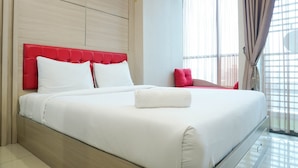 A modern hotel room with a large bed, a red headboard, and a view of the city through large windows. - Fully Furnished With Cozy Studio Gp Plaza Apartment (Jakarta)