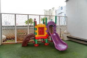Children can play safely within this enclosed play area featuring a colorful play structure with a slide and climbing wall.