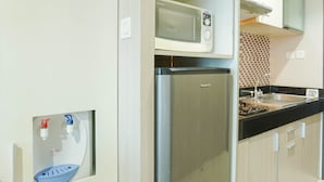 A compact kitchen with a microwave, refrigerator, sink, and a water dispenser. - Fully Furnished With Cozy Studio Gp Plaza Apartment (Jakarta)