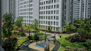 A residential building with a playground in the foreground and high-rise buildings in the background. - Nice And Fresh 2Br Apartment At M-Town Residence (Gading Serpong)