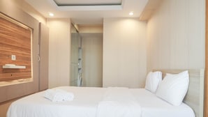 Une chambre d’hôtel moderne avec un grand lit, un mur recouvert de panneaux en bois et une étagère intégrée.
