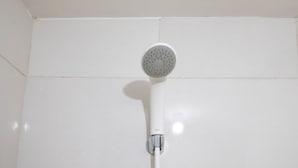 Un pommeau de douche fixé sur un mur recouvert de carreaux blancs.