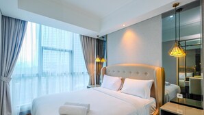 Een moderne hotelkamer met een groot bed, nachtkastje, spiegel en uitzicht op de stad door grote ramen.