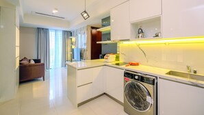 Een moderne keuken met een ingebouwde wasmachine, een zithoek met een bank en een groot raam met gordijnen.