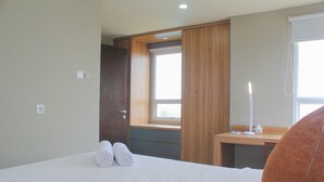 Ein Hotelzimmer mit Bett, Schreibtisch, Fenster und Tür.