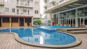Piscina com bordas azulejadas, rodeada por um deck de madeira.