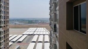 A high-rise building with multiple balconies and a view of a distant landscape including fields and a bridge. - Minimalist And Comfortable Studio Apartment Tokyo Riverside Pik 2 (Teluknaga)