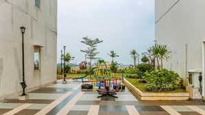 A playground with a climbing structure and a slide, surrounded by a paved area with a lamp post and greenery. - Comfort Studio At Margonda Residence 3 Apartment (Depok)