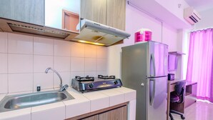 A modern kitchen with a gas stove, sink, and stainless steel refrigerator. - Comfort Studio At Margonda Residence 3 Apartment (Depok)