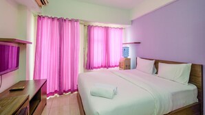 A hotel room with a bed, a desk, a TV, and curtains. - Comfort Studio At Margonda Residence 3 Apartment (Depok)