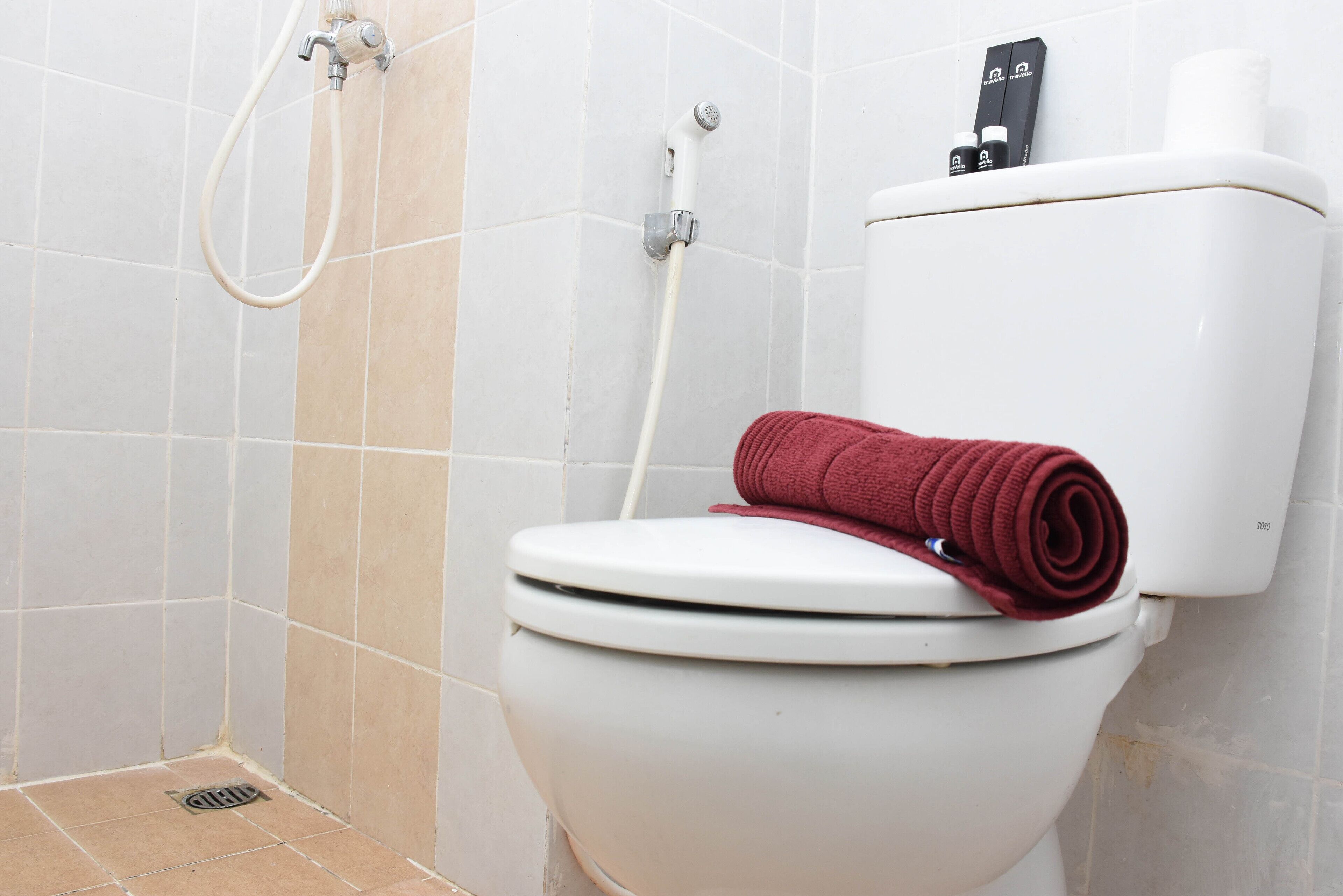 A bathroom with a toilet, a shower, and a toilet paper holder.