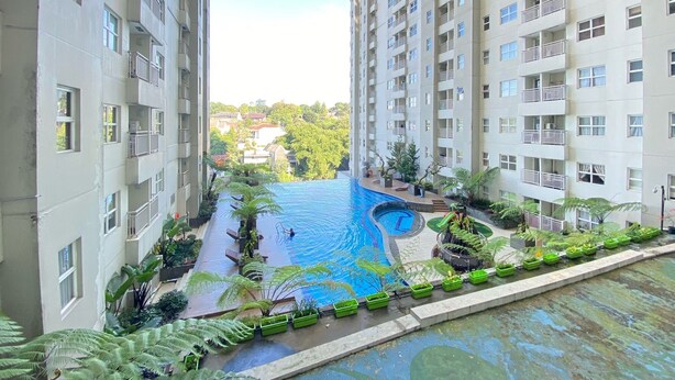 Un edificio residencial con piscina rodeada de vegetación.